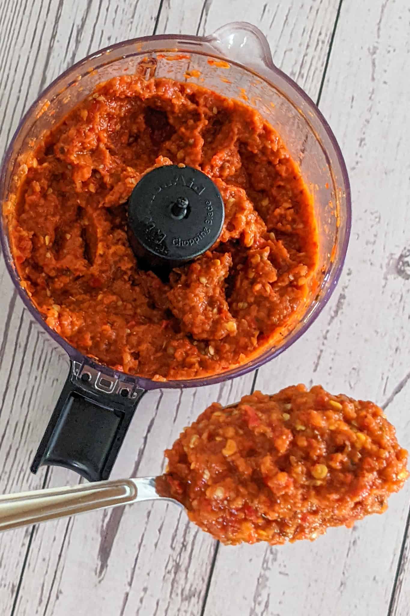 Vibrant harissa sauce blended with eggplant in a food processor, ready for culinary use.